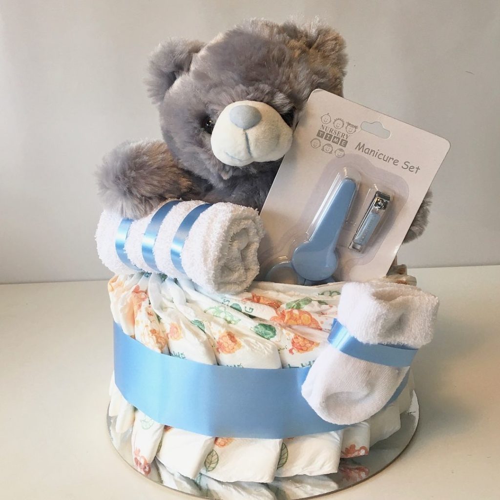 Snygg neutral blöjtårta i grått. Denna blöjtårta är en passande present till babyshower när du ännu inte vet könet på den kommande bäbisen och ändå behöver köpa en present som är rätt och blir uppskattad. Neutral blöjtårta går i grått så den passar både till om det blir en ficka eller en pojke. Innehåller blöjor från Libero, en babyhandduk, ett par babysockor, ett manikyrset bestående av en babyvänlig sax och nagelklippare och så förstås den söta grå teddybjörnen.