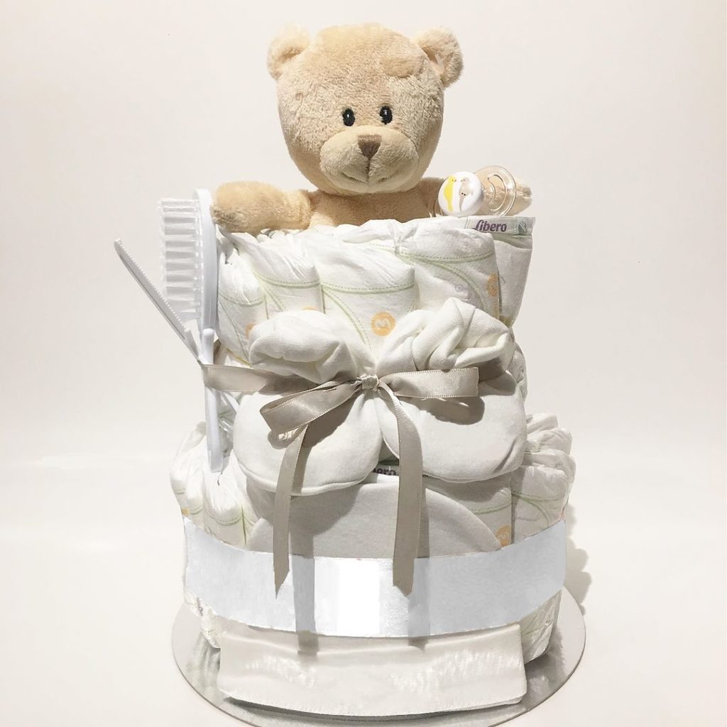 Snygg neutral blöjtårta i grått. Denna blöjtårta är en passande present till babyshower när du ännu inte vet könet på den kommande bäbisen och ändå behöver köpa en present som är rätt och blir uppskattad. Neutral blöjtårta går i grått så den passar både till om det blir en ficka eller en pojke. Innehåller blöjor från Libero, en babyhandduk, ett par babysockor, ett manikyrset bestående av en babyvänlig sax och nagelklippare och så förstås den söta grå teddybjörnen.